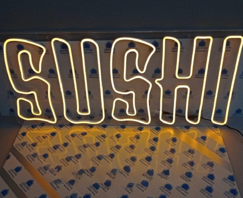 Яскравий жовтий LED неон напис "Sushi" для оформлення фасаду чи вітрини.